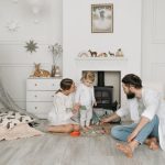 Warm family scene of parents playing with their daughter in a cozy white room.