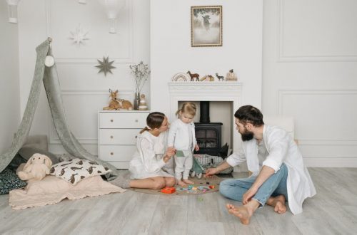 Warm family scene of parents playing with their daughter in a cozy white room.
